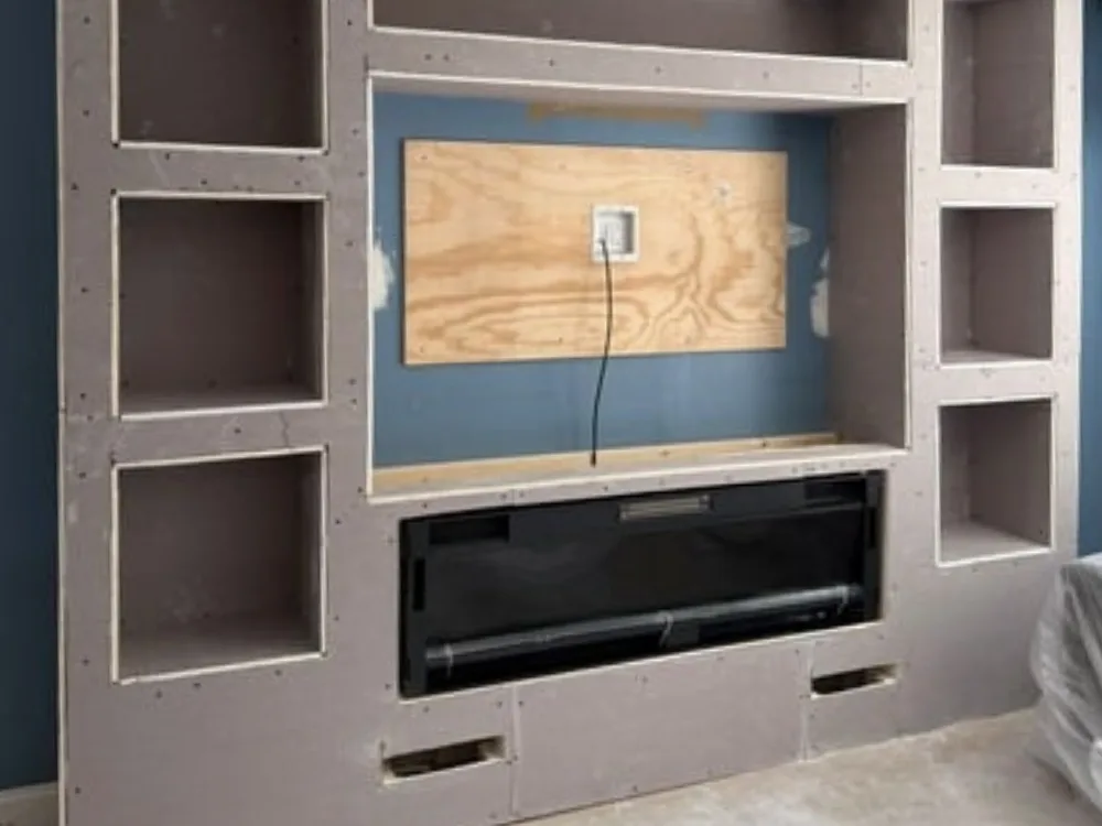 Entertainment wall framework with shelving and recessed fireplace.