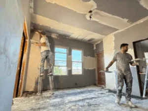 Drywall installation work with workers applying finishing touches.