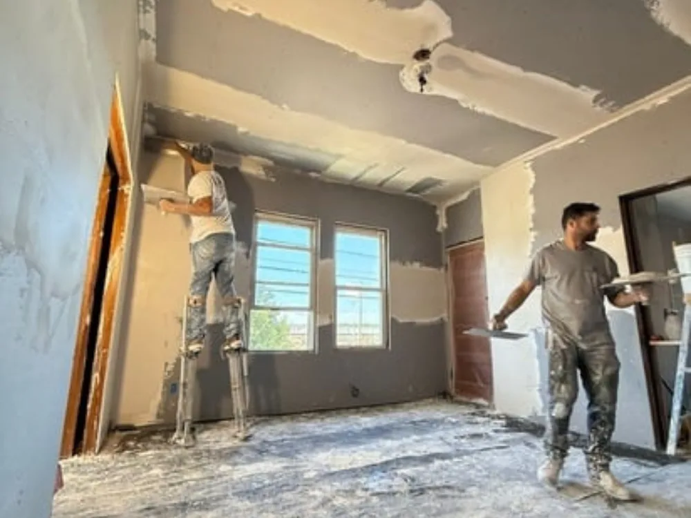 Drywall installation work with workers applying finishing touches.