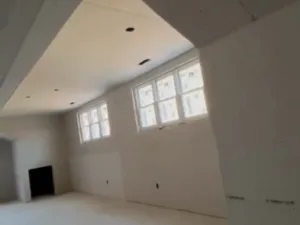 Drywall installation and finishing in large open living area with ceiling cutouts