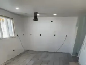 Kitchen renovation preparation with exposed subfloor and ceiling vent installation.